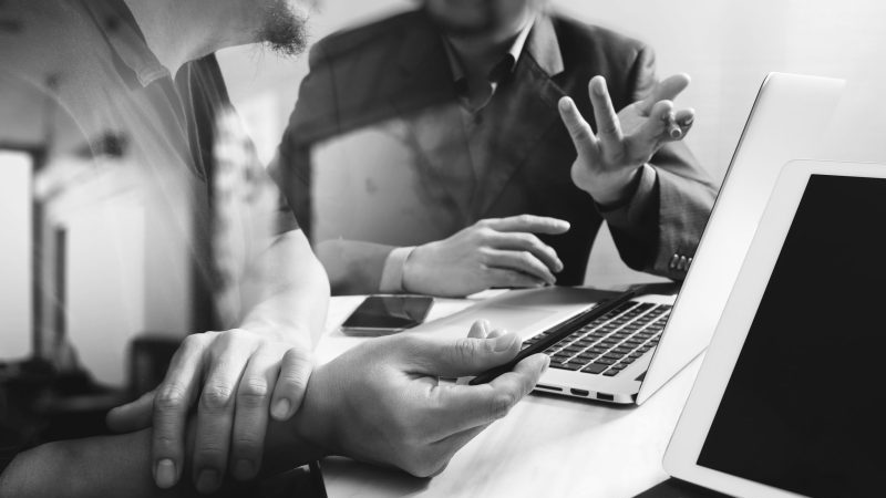 A photograph of two people working together at a computer.
